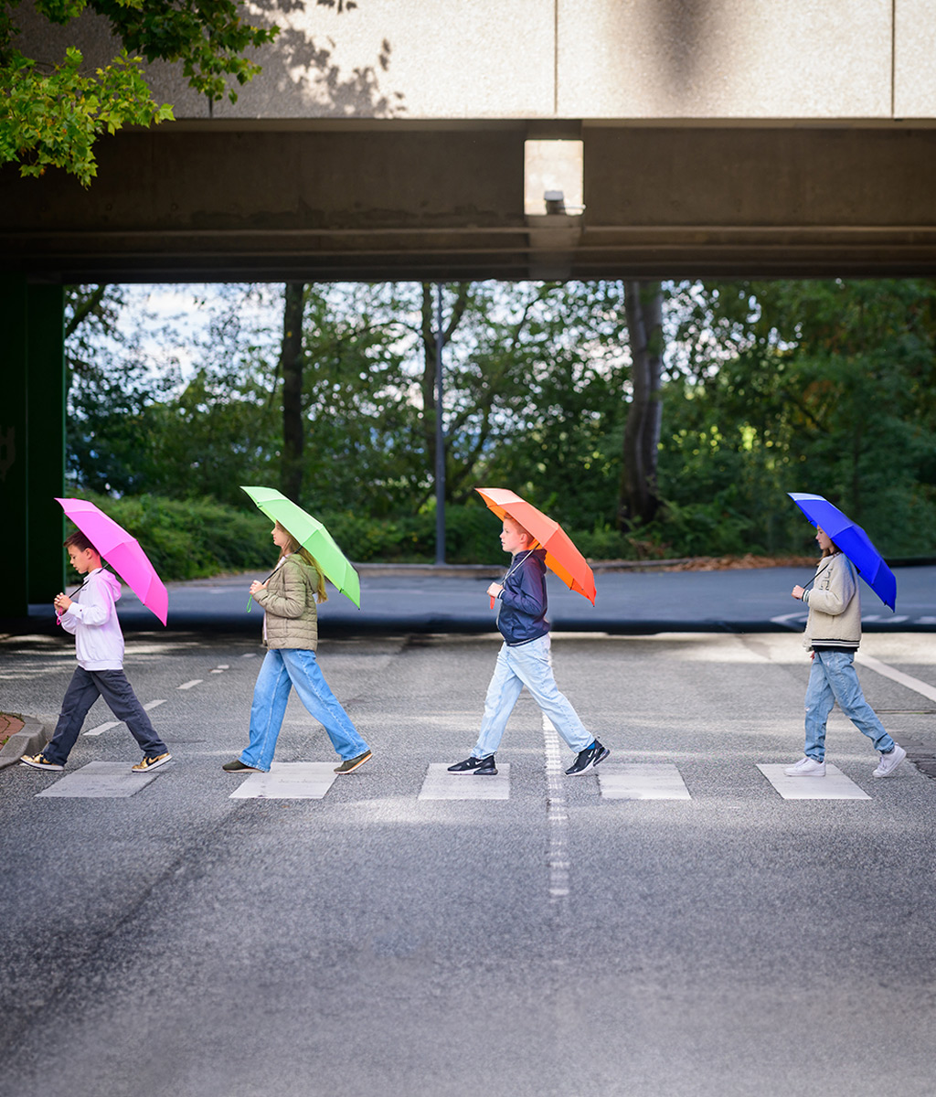 Children with colourful umbrellas on zebra crossings