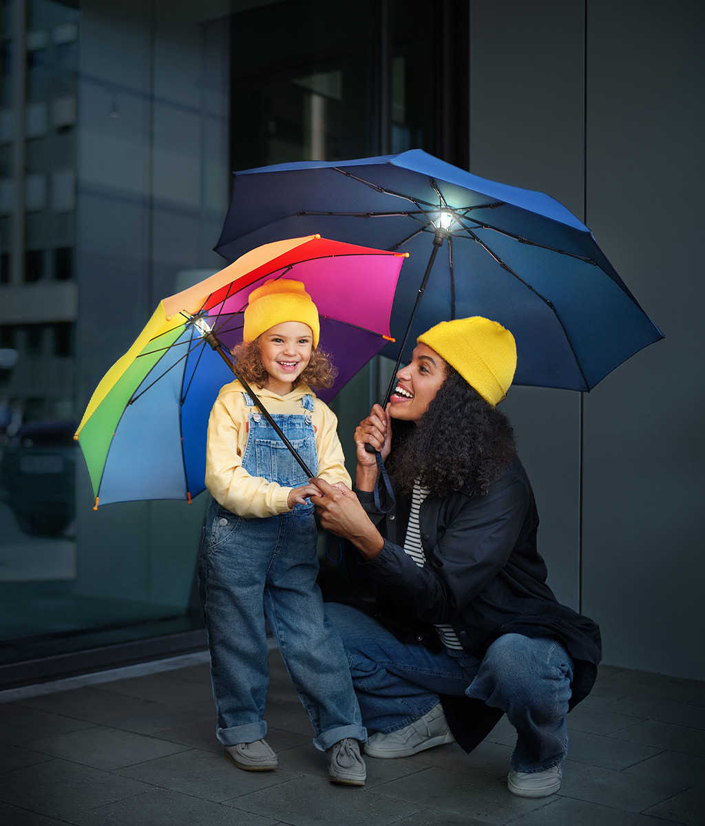 Mutter und Kind mit beleuchteten Regenschirmen