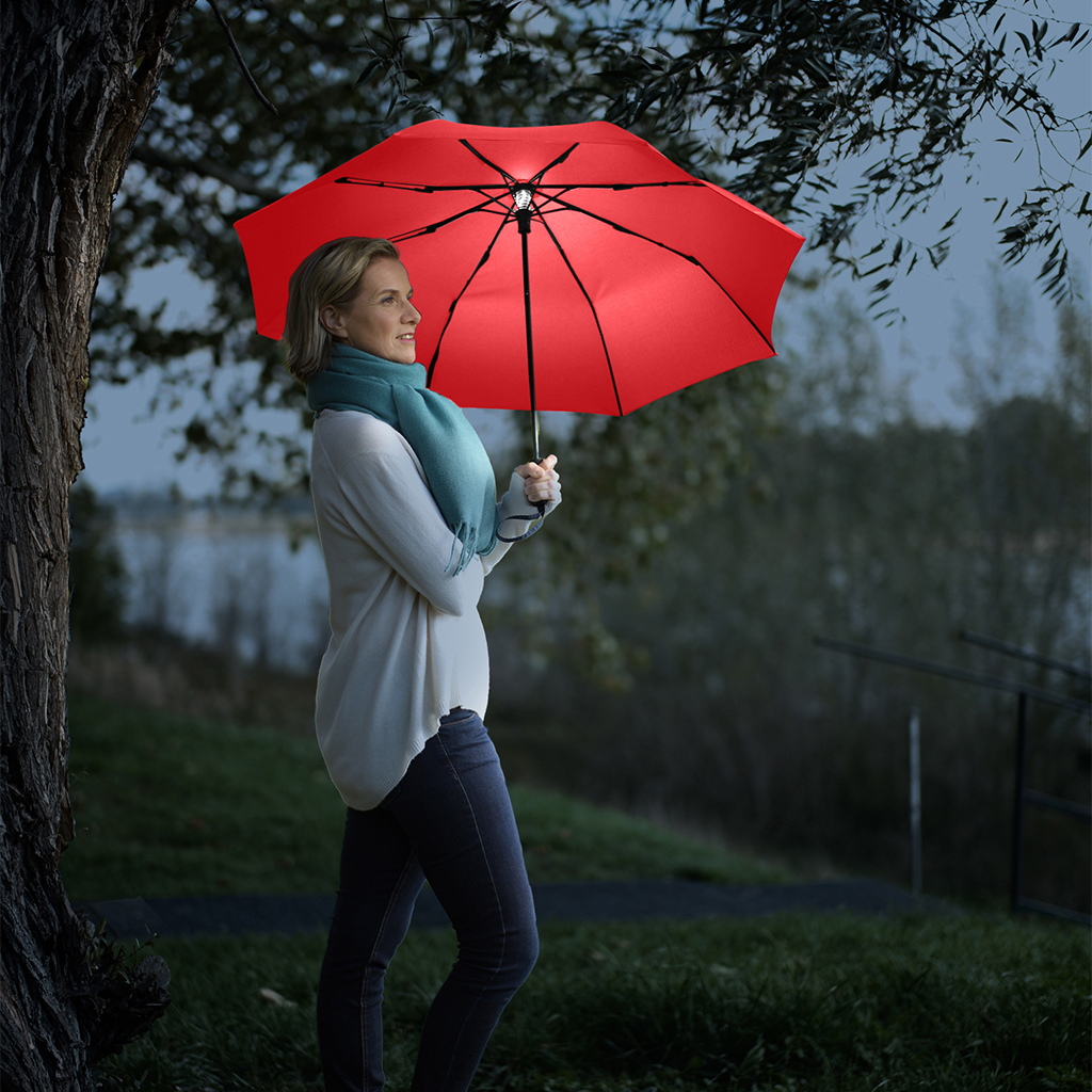 Woman with red FARE Skylight umbrella with LED lighting at night