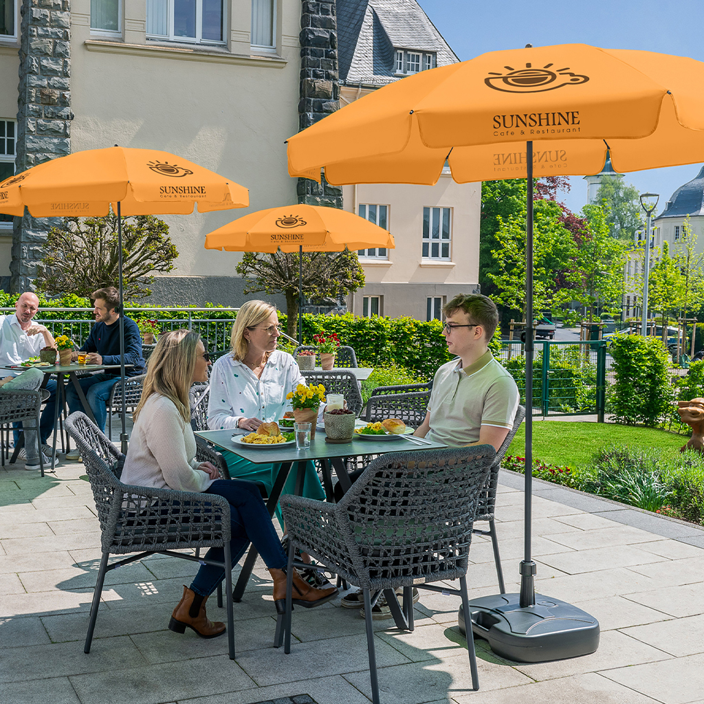 Leute auf Cafe-Terrasse unter Sonnenschirmen